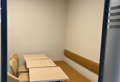 Small breakout booth with mustard yellow bench seating and light wood tables.