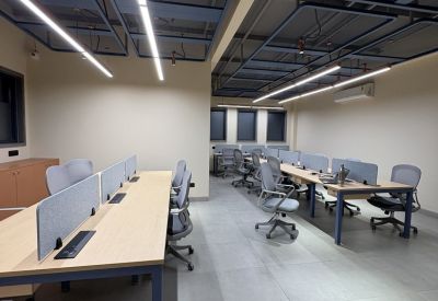 Spacious open-plan workspace with multiple wooden desks and industrial ceiling design.