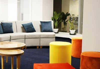 Bright lounge area with a curved sofa and vibrant orange and yellow stools.