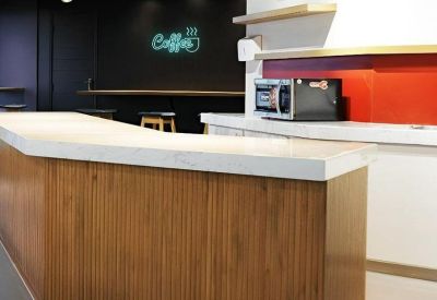 Coffee station with a fluted wood counter and neon signage.