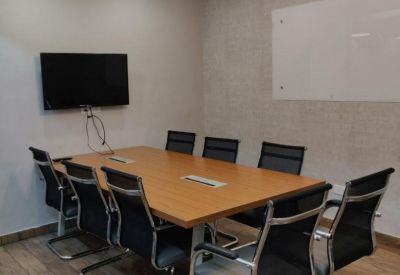 Professional meeting room with a wooden table, ergonomic chairs, and wall-mounted television.