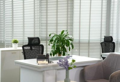 Bright workspace with a white desk, purple flowers, and large windows with blinds.
