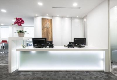 Modern communal area with a curved white counter, high red bar stools, and grey patterned carpet.