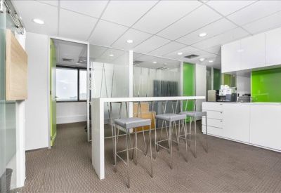 Modern breakout area featuring a white high-top table, grey bar stools, and lime green accents.