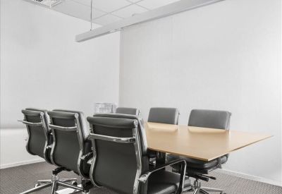 Sleek conference room with six black leather chairs around a light wood table.