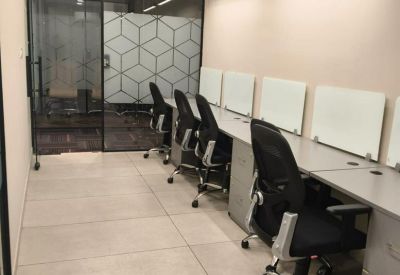 Linear workspace with multiple desks, black ergonomic chairs, and geometric frosted glass partitions.