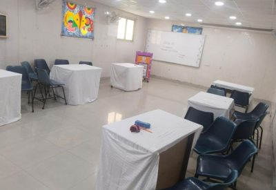 Meeting room with white tables, blue chairs, and a white presentation board.