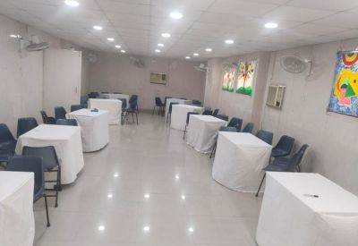 Brightly lit open-plan hall with several white tables and seating clusters.