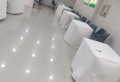Long view of a multipurpose room featuring white tables and vibrant wall art.