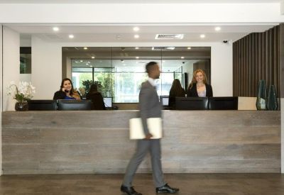 Professional reception area with a long timber-fronted desk and staff assisting visitors.
