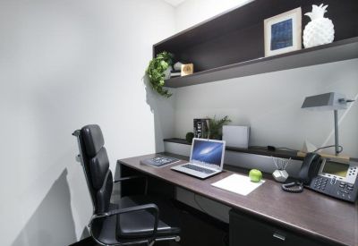 Dark wood executive desk featuring a laptop, desk lamp, and overhead shelving.