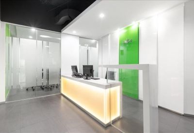 Bright reception area featuring a warm backlit desk and green feature wall.