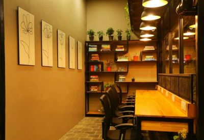 Narrow coworking space with a row of desks, bookshelves, and flower line art on the wall.