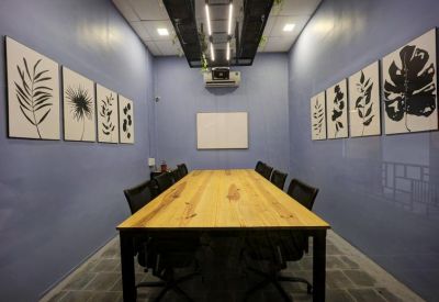 Professional meeting room with a large wooden table, black chairs, and botanical wall art.