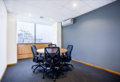 Meeting room with a round wooden table and dark grey feature wall.