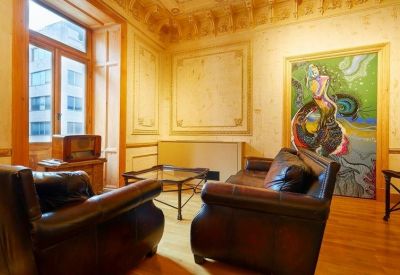 Lounge area with leather armchairs, a glass coffee table, and vibrant abstract wall art.
