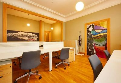Bright workspace featuring rows of modern desks, ergonomic chairs, and large framed wall graphics.