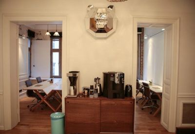 Communal coffee station with espresso machines and views into adjacent workspaces through open doorways.