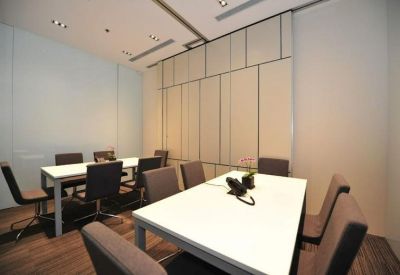 A professional boardroom featuring a white table, modern grey chairs, and sleek wall panels.