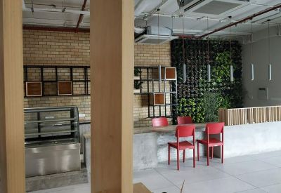 Cafe-style breakout area with a service counter, red chairs, and a lush green plant wall.