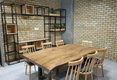 Meeting area with a large live-edge wooden table and industrial-style shelving against a brick wall.