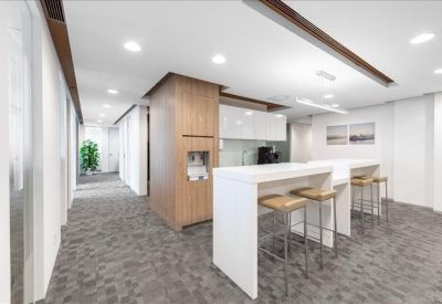 Modern kitchen and breakout area with white breakfast bars and high stools.