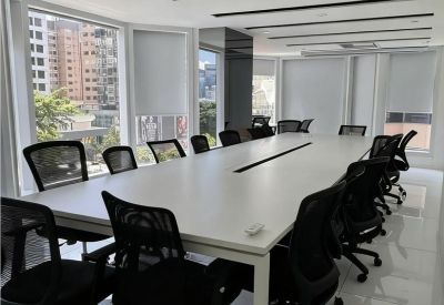 Bright conference room with a long white table, black mesh chairs, and large windows.
