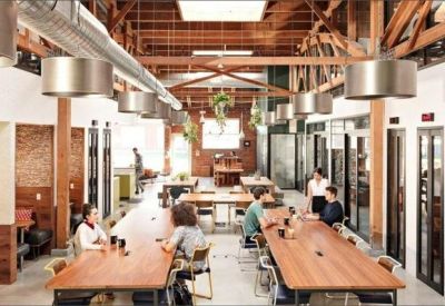 Industrial style meeting space with long wooden tables, exposed timber beams, and large metal light fixtures.