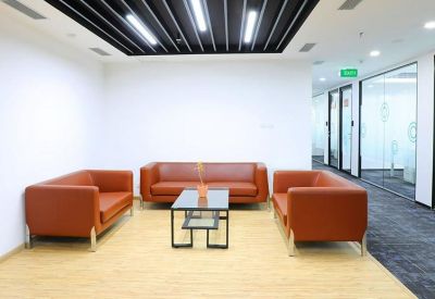 Bright lounge area with three orange leather sofas and a glass coffee table.