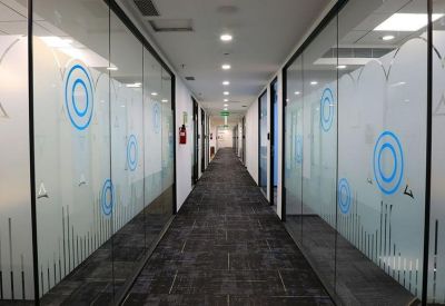Long office corridor with glass walls featuring blue circular graphics.