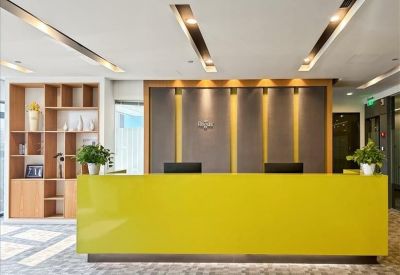 Modern reception area featuring a bold yellow front desk and warm decorative lighting.