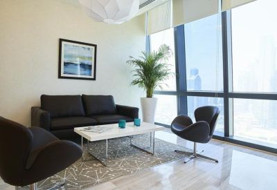 Small reception or waiting area with a black sofa, stylish chairs, and a potted palm.