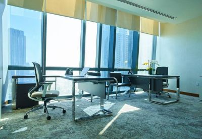 Professional private office with an L-shaped desk and large windows for natural light.