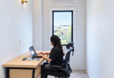 Long workstation area with a person working on a laptop near a window.