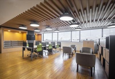 Bright coworking space with wooden slat ceilings, vibrant green chairs, and lounge seating.