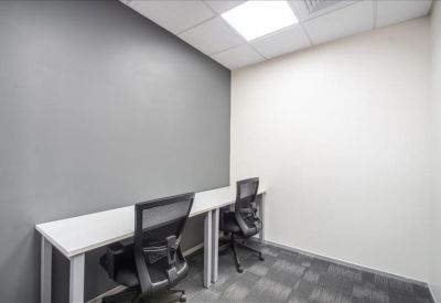 Minimalist internal two-person office suite with white desks and grey accent wall.