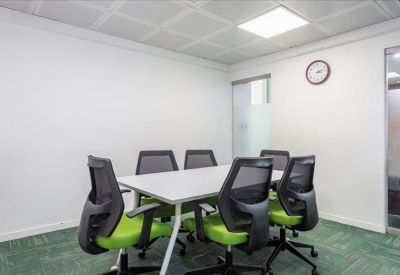 Six-person meeting room with green-cushioned chairs and a bright ceiling light.