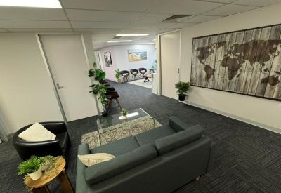 Breakout space with a grey sofa, glass coffee table, and a world map wall mural.