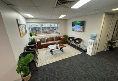 Lounge area with a leather sofa, coffee table, and a water cooler near a window.