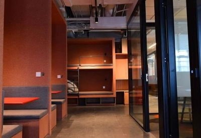 Private phone booths and breakout pods with orange acoustic paneling and glass doors.