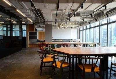 Modern meeting area featuring large wooden tables, designer chairs, and floor-to-ceiling windows.