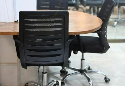Black mesh ergonomic chairs surrounding a round wooden meeting table.