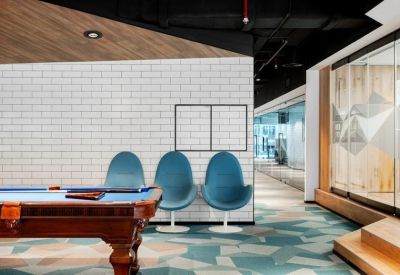 Recreational zone with a pool table and a row of iconic teal egg chairs against a brick-patterned wall.