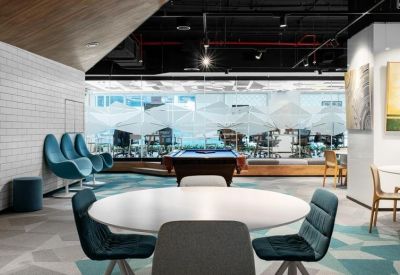 Casual breakout area featuring teal lounge chairs and a pool table under an industrial ceiling.