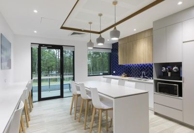 Modern kitchen and dining area with blue tiled backsplash and white island bench.