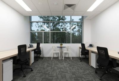 Bright office suite with four workstations and views of lush greenery.