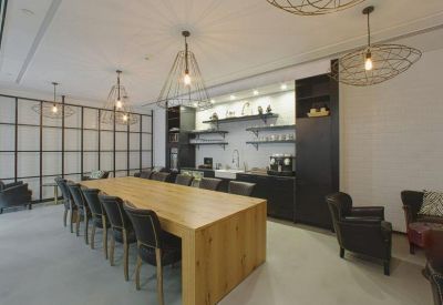 Warm communal breakout area with a large wooden table and modern pantry.