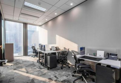 Bright multi-person office suite with ergonomic workstations and large windows.