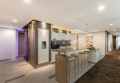 Modern communal kitchen area with a high breakfast bar and white cabinetry.