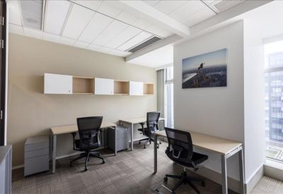 Bright office space with three desks, black mesh chairs, and a seaside wall art piece.
